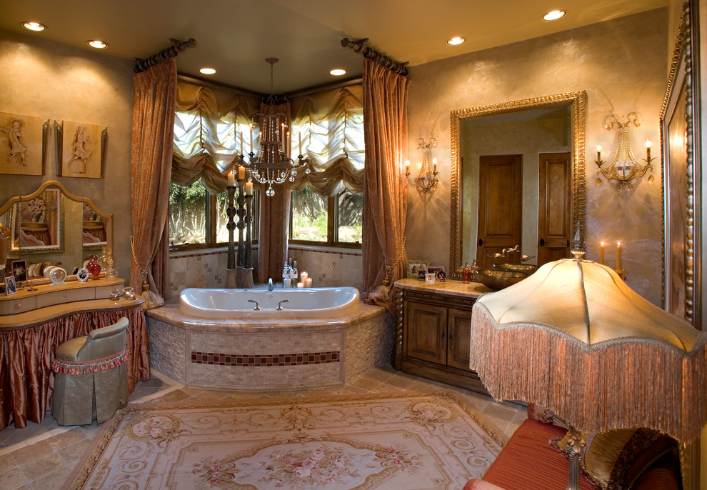 Exemple d'une grande salle de bain principale méditerranéenne en bois foncé avec une vasque, un placard en trompe-l'oeil, un plan de toilette en marbre, une baignoire d'angle, des carreaux de porcelaine, un mur beige, un sol en travertin et un sol beige.