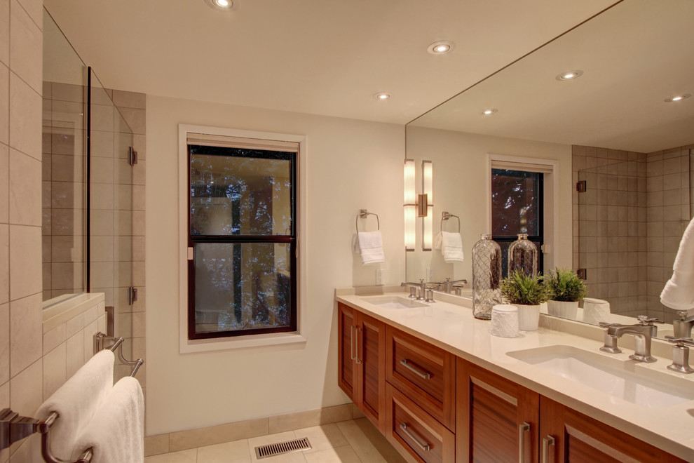 Bild på ett mellanstort funkis en-suite badrum, med vita skåp, ett badkar i en alkov, en dusch/badkar-kombination, vit kakel, porslinskakel, beige väggar, travertin golv, ett undermonterad handfat och granitbänkskiva