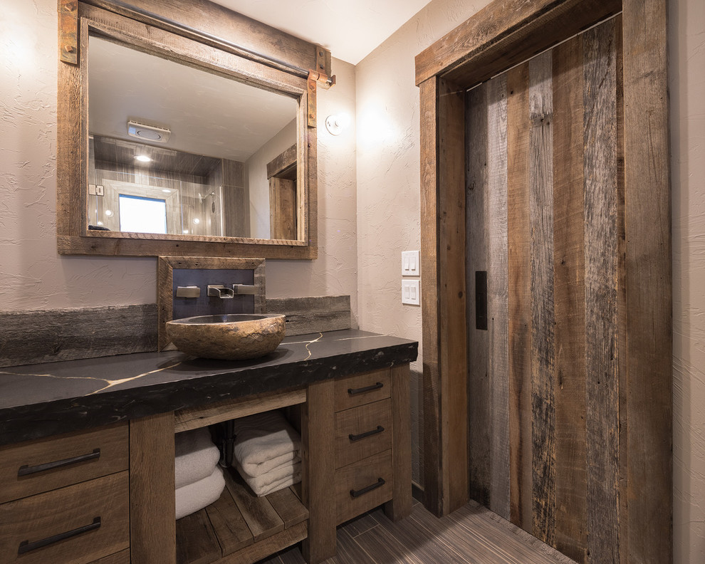 Exemple d'une grande salle de bain montagne en bois brun avec un placard à porte plane, un mur beige, un sol en carrelage de porcelaine, une vasque, un sol marron et une cabine de douche à porte battante.