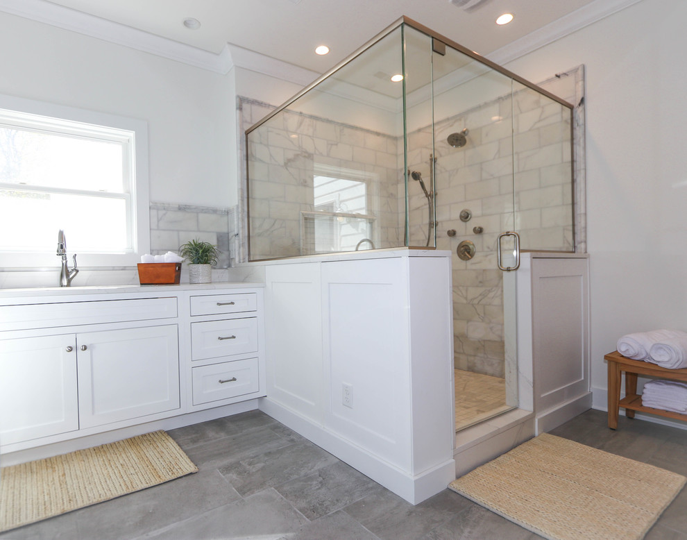 Example of a transitional marble tile and gray tile gray floor corner shower design in Other with white walls, a hinged shower door, recessed-panel cabinets and white cabinets