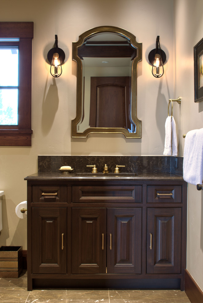 Foto på ett vintage brun badrum med dusch, med luckor med profilerade fronter, skåp i mörkt trä, en toalettstol med separat cisternkåpa, beige väggar, marmorgolv, ett undermonterad handfat, marmorbänkskiva och brunt golv