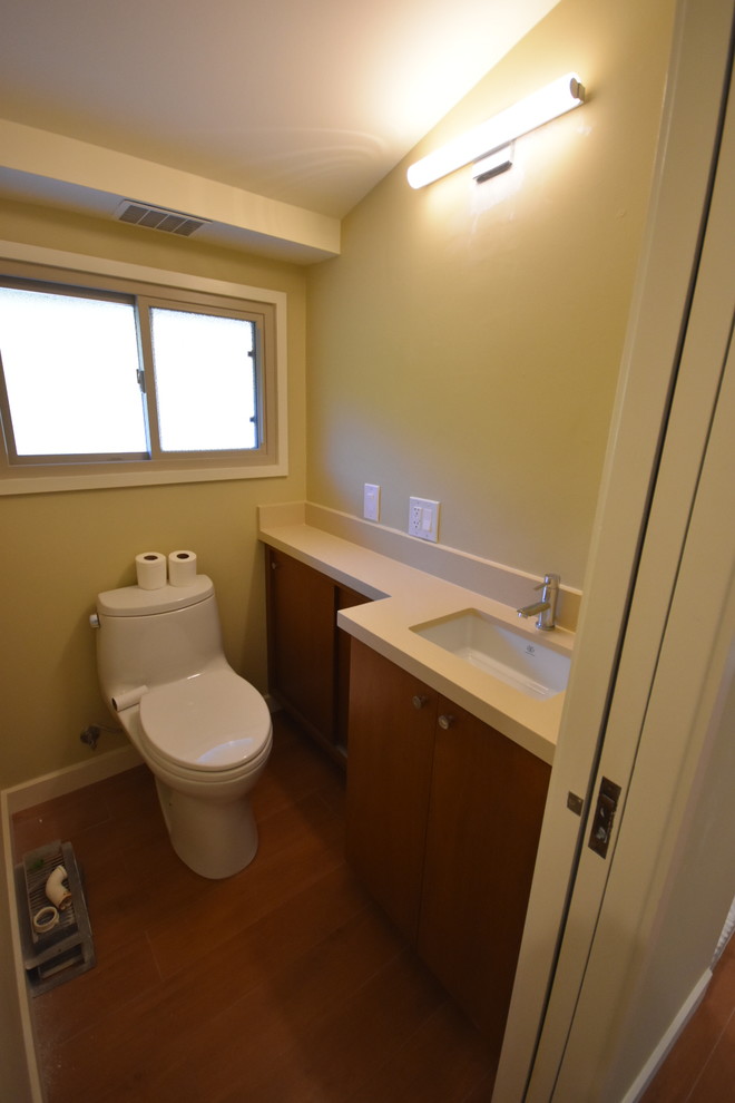 Cette image montre une grande salle de bain principale minimaliste en bois brun avec un placard à porte plane, une baignoire indépendante, une douche d'angle, WC à poser, un carrelage beige, des carreaux de porcelaine, un mur beige, un sol en galet, un lavabo encastré, un plan de toilette en cuivre et un sol beige.