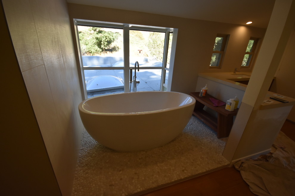 Example of a large minimalist master beige tile and porcelain tile pebble tile floor and beige floor bathroom design in Los Angeles with flat-panel cabinets, medium tone wood cabinets, a one-piece toilet, beige walls, an undermount sink and copper countertops