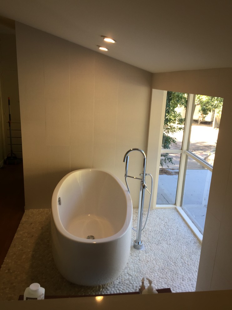 Cette photo montre une grande salle de bain principale moderne en bois brun avec un placard à porte plane, une baignoire indépendante, une douche d'angle, WC à poser, un carrelage beige, des carreaux de porcelaine, un mur beige, un sol en galet, un lavabo encastré, un plan de toilette en cuivre et un sol beige.