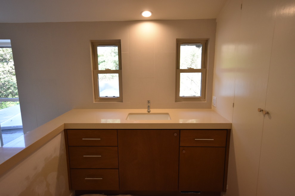 Idées déco pour une grande salle de bain principale moderne en bois brun avec un placard à porte plane, une baignoire indépendante, une douche d'angle, WC à poser, un carrelage beige, des carreaux de porcelaine, un mur beige, un sol en galet, un lavabo encastré, un plan de toilette en cuivre et un sol beige.