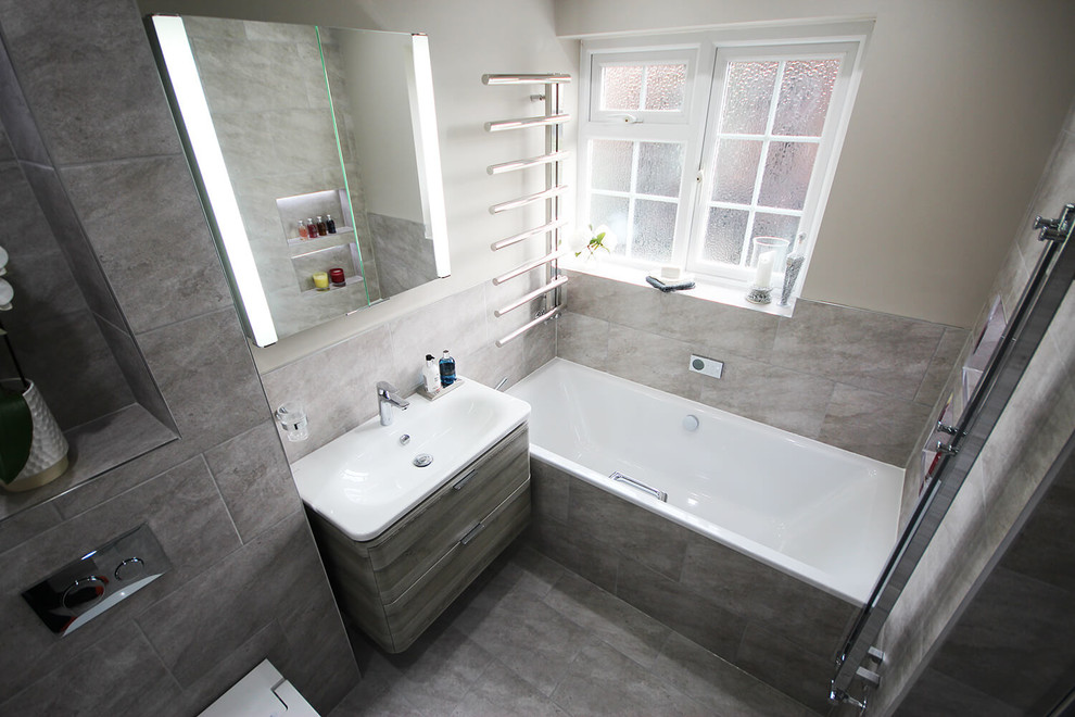 Exempel på ett mellanstort modernt en-suite badrum, med ett platsbyggt badkar, en kantlös dusch, en vägghängd toalettstol, grå kakel, porslinskakel, grå väggar, klinkergolv i porslin, ett undermonterad handfat, grått golv och dusch med gångjärnsdörr