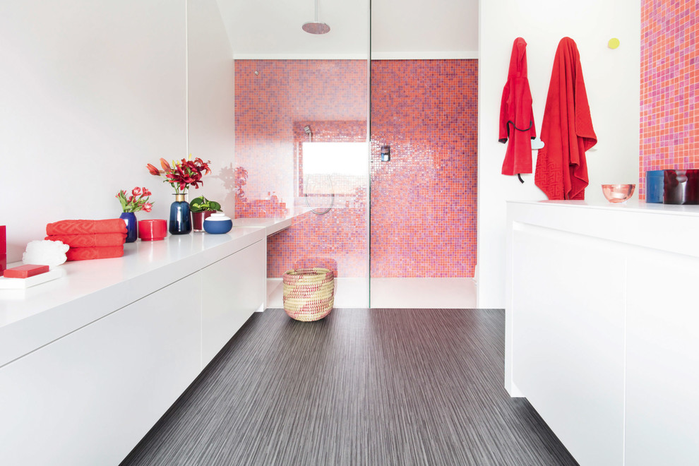 На фото: ванная комната в современном стиле с плоскими фасадами, белыми фасадами, душем в нише, разноцветной плиткой, оранжевой плиткой, розовой плиткой, красной плиткой, плиткой мозаикой, белыми стенами, полом из винила, серым полом, открытым душем и белой столешницей