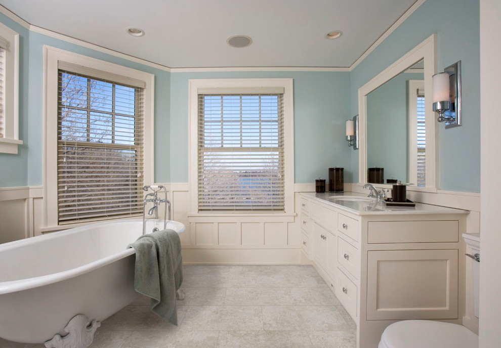 Inspiration for a mid-sized timeless master white tile freestanding bathtub remodel in Toronto with a drop-in sink, recessed-panel cabinets, beige cabinets, marble countertops, a one-piece toilet and blue walls