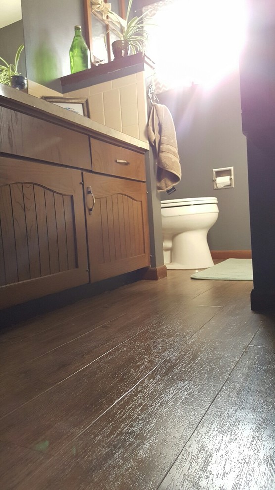 Photo of a small rural family bathroom in Other with recessed-panel cabinets, brown cabinets, a built-in bath, a two-piece toilet, yellow tiles, ceramic tiles, grey walls, vinyl flooring, a built-in sink and laminate worktops.