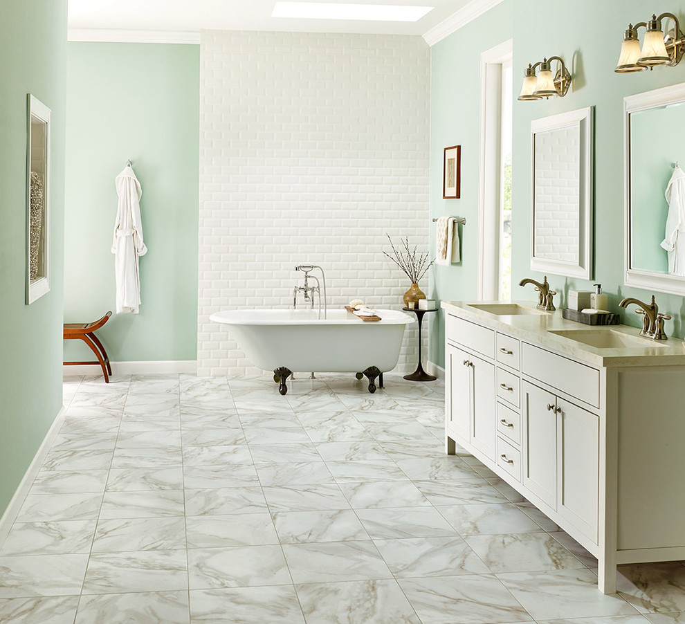 Cette image montre une salle de bain traditionnelle avec un placard à porte shaker, des portes de placard blanches, une baignoire indépendante, un carrelage blanc, un mur vert et un sol en vinyl.