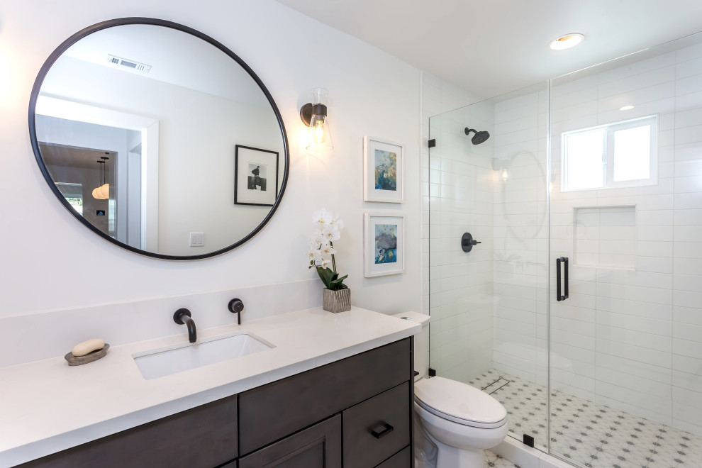 Example of a cottage white tile and subway tile porcelain tile, white floor and single-sink alcove shower design in Los Angeles with shaker cabinets, black cabinets, a one-piece toilet, white walls, an undermount sink, quartzite countertops, a hinged shower door, white countertops and a built-in vanity