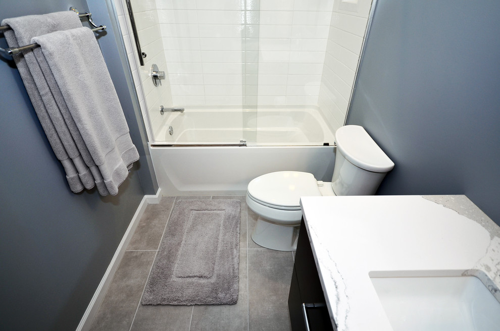 Bathroom - mid-sized modern kids' white tile and porcelain tile ceramic tile and gray floor bathroom idea in Charlotte with flat-panel cabinets, black cabinets, a two-piece toilet, blue walls, an undermount sink and quartz countertops