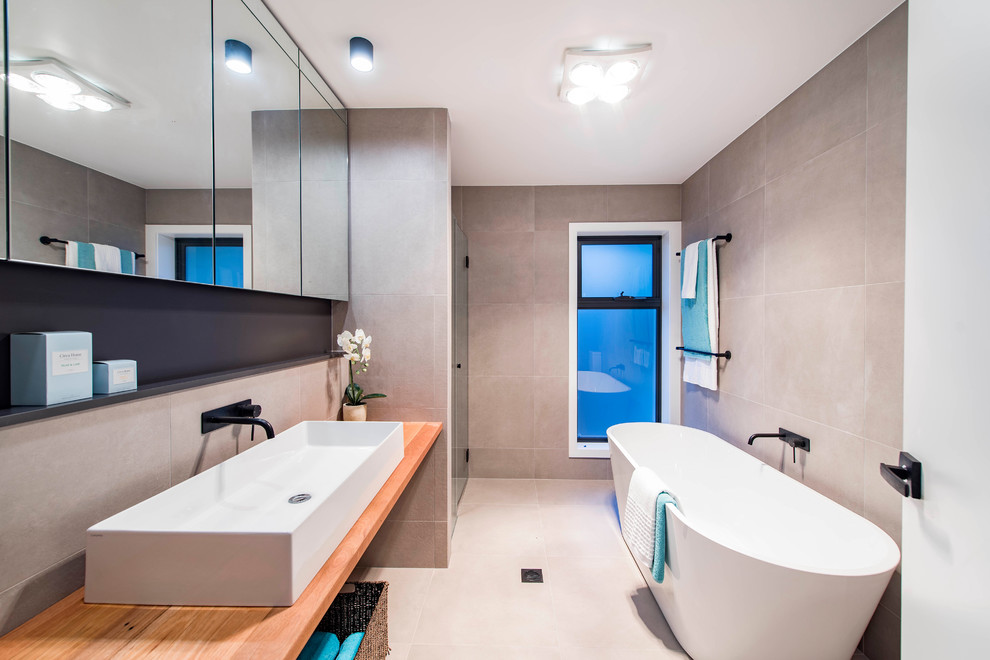 Cette image montre une salle de bain marine avec une baignoire indépendante, un carrelage gris et des carreaux de céramique.