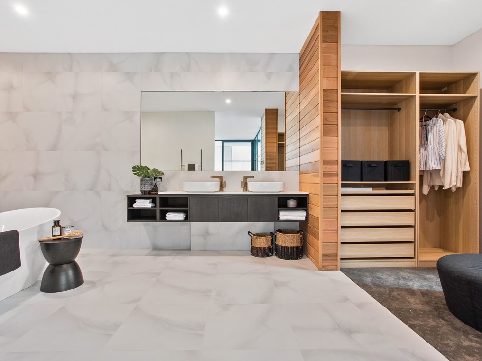 Идея дизайна: главная ванная комната в современном стиле с плоскими фасадами, серыми фасадами, отдельно стоящей ванной, серой плиткой, белой плиткой, серыми стенами, настольной раковиной, белым полом и белой столешницей