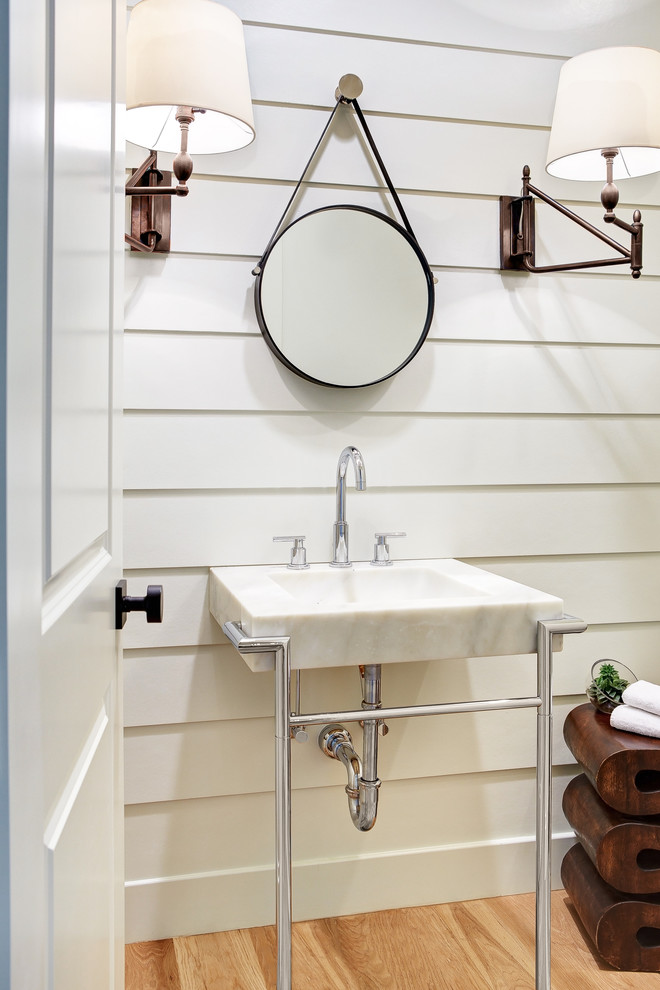 Foto de cuarto de baño minimalista de tamaño medio con lavabo con pedestal, encimera de mármol, sanitario de una pieza, paredes blancas, suelo de madera clara y aseo y ducha