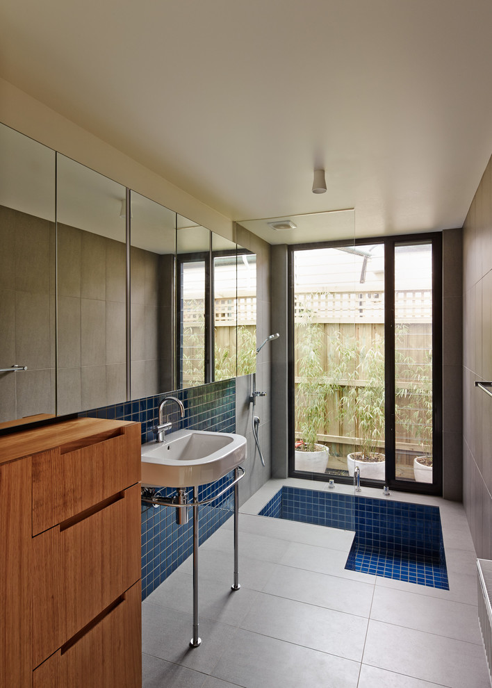 Contemporary ensuite bathroom in Melbourne with a console sink, flat-panel cabinets, medium wood cabinets, an alcove shower, blue tiles, mosaic tiles, beige walls and a submerged bath.