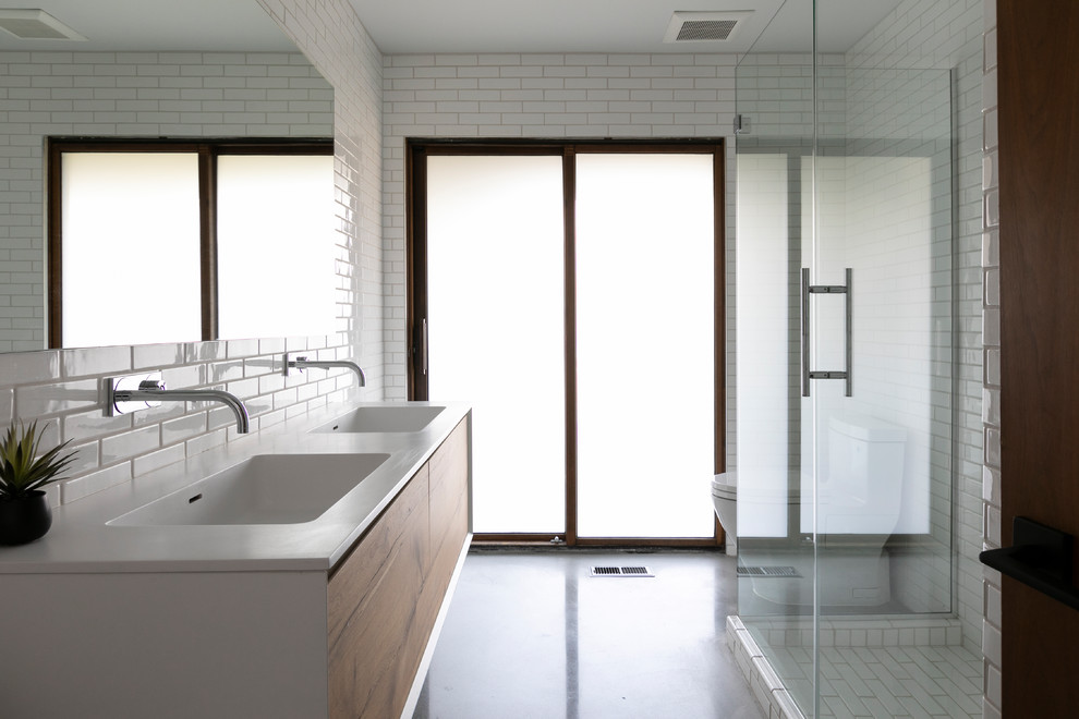 Esempio di una stanza da bagno moderna con ante lisce, ante in legno scuro, doccia ad angolo, piastrelle bianche, pareti gialle, pavimento in cemento, lavabo integrato, pavimento grigio, porta doccia a battente e top bianco