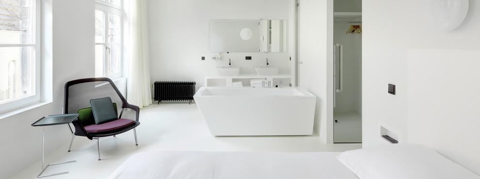 Medium sized contemporary ensuite bathroom in Surrey with open cabinets, white cabinets, a freestanding bath, white tiles, white walls, concrete flooring, a vessel sink and solid surface worktops.