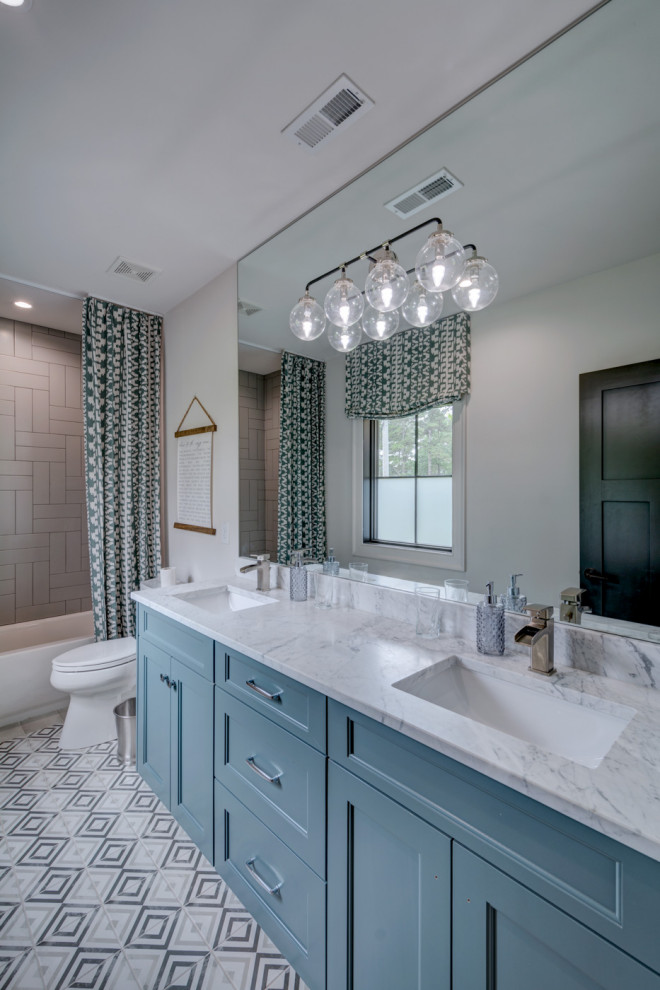 Пример оригинального дизайна: главная ванная комната среднего размера с фасадами с утопленной филенкой, синими фасадами, ванной в нише, душем над ванной, раздельным унитазом, серой плиткой, керамической плиткой, белыми стенами, полом из цементной плитки, врезной раковиной, мраморной столешницей, серым полом, шторкой для ванной, разноцветной столешницей, тумбой под две раковины и встроенной тумбой