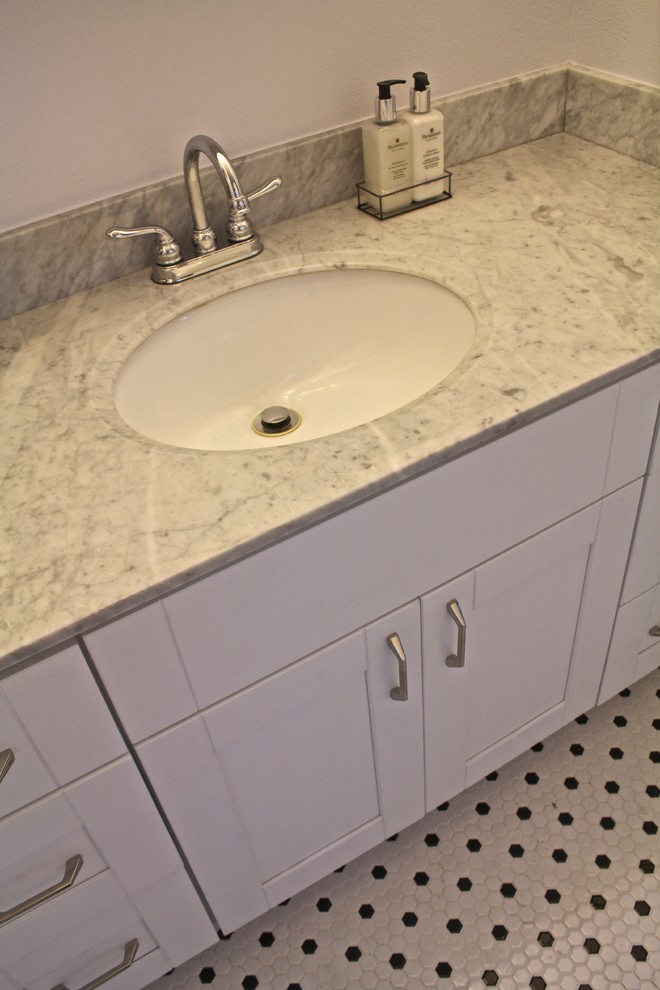Bild på ett mellanstort funkis badrum med dusch, med skåp i shakerstil, vita skåp, en toalettstol med separat cisternkåpa, beige väggar, linoleumgolv, ett undermonterad handfat och marmorbänkskiva