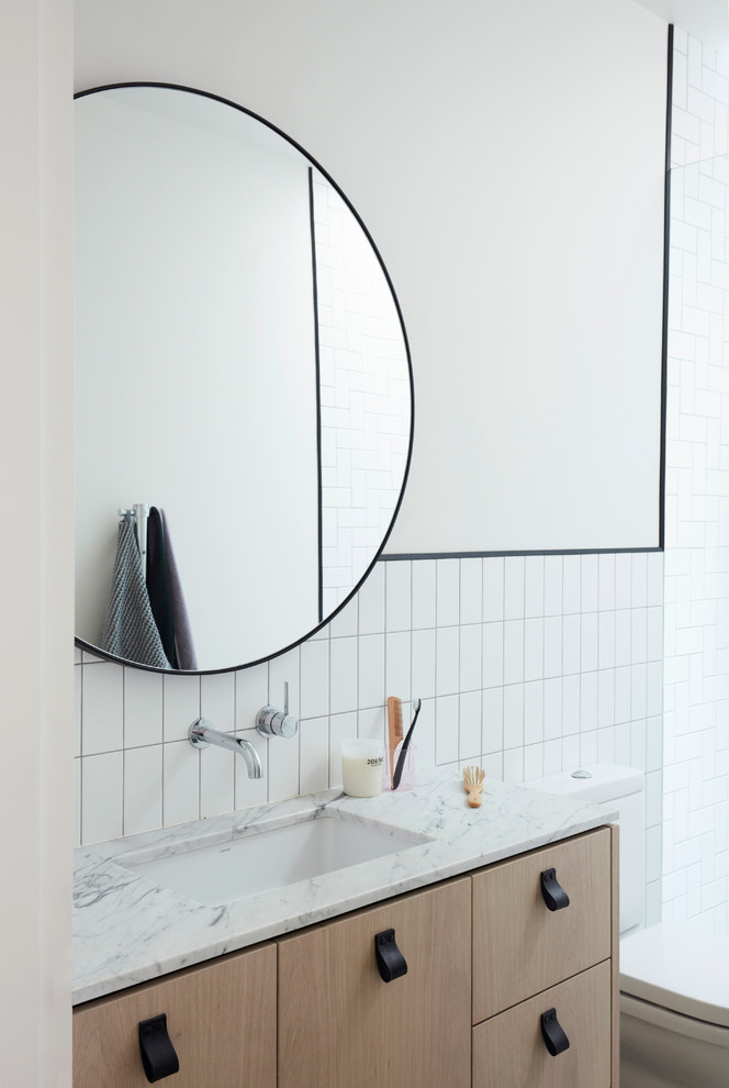 Стильный дизайн: ванная комната в современном стиле с плоскими фасадами, светлыми деревянными фасадами, белой плиткой, белыми стенами, врезной раковиной и белой столешницей - последний тренд