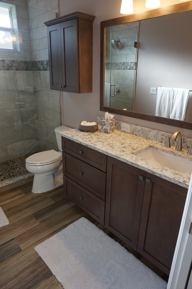 Mid-sized transitional master ceramic tile medium tone wood floor and brown floor alcove shower photo in Miami with shaker cabinets, dark wood cabinets, a two-piece toilet, beige walls, an undermount sink, granite countertops and a hinged shower door