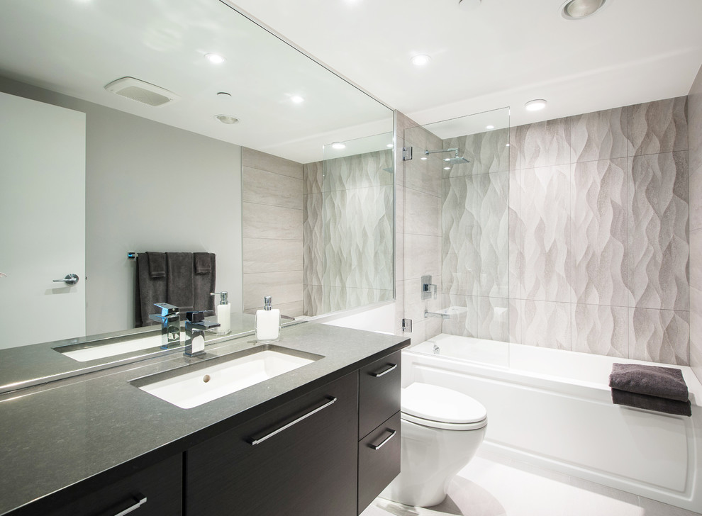 Inspiration for a contemporary gray tile and ceramic tile ceramic tile tub/shower combo remodel in Vancouver with an undermount sink, flat-panel cabinets, medium tone wood cabinets, quartz countertops, a one-piece toilet and gray walls