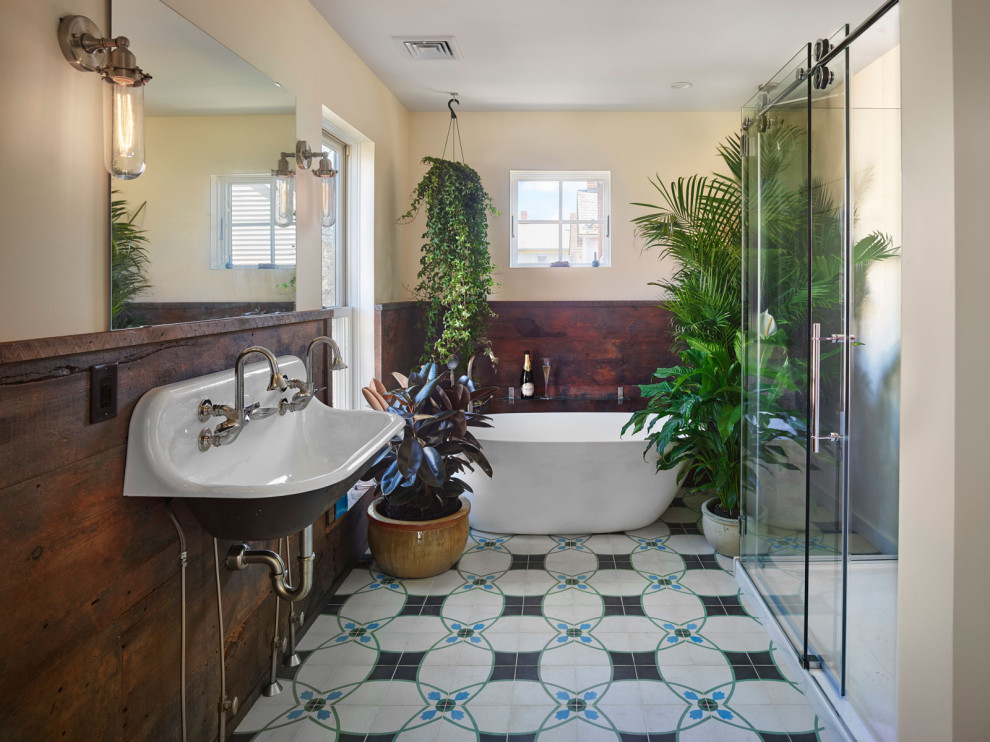 Large eclectic ensuite bathroom in Philadelphia with a freestanding bath, an alcove shower, cement flooring, a wall-mounted sink, a sliding door and wainscoting.