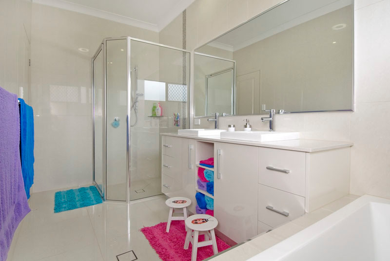 Cette photo montre une salle de bain tendance de taille moyenne pour enfant avec des portes de placard blanches, un plan de toilette en calcaire, un carrelage beige et des carreaux de porcelaine.