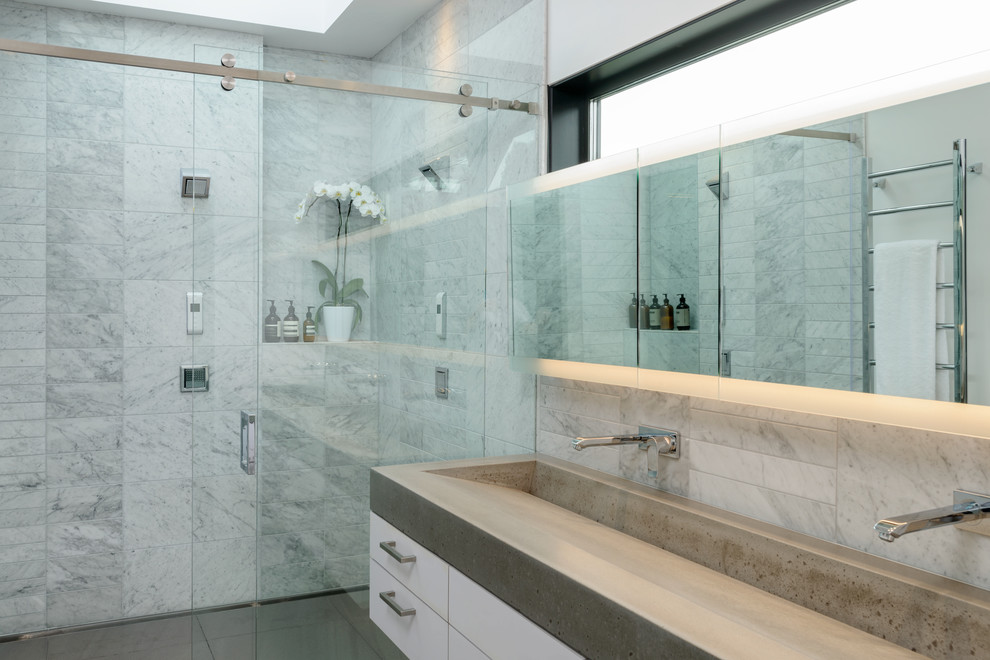 Example of a mid-sized trendy gray floor alcove shower design in Seattle with flat-panel cabinets, white cabinets, white walls, a trough sink and gray countertops