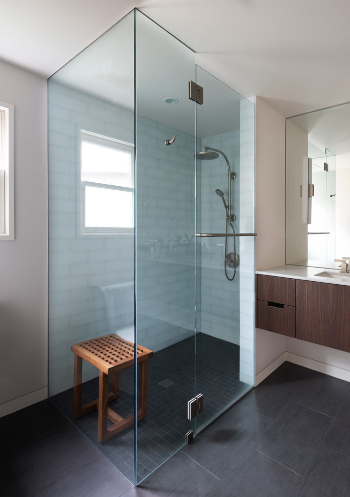 Photo of a medium sized modern ensuite bathroom in Seattle with flat-panel cabinets, dark wood cabinets, a corner shower, white tiles, glass tiles, white walls, ceramic flooring, a submerged sink, solid surface worktops, black floors, a hinged door and white worktops.