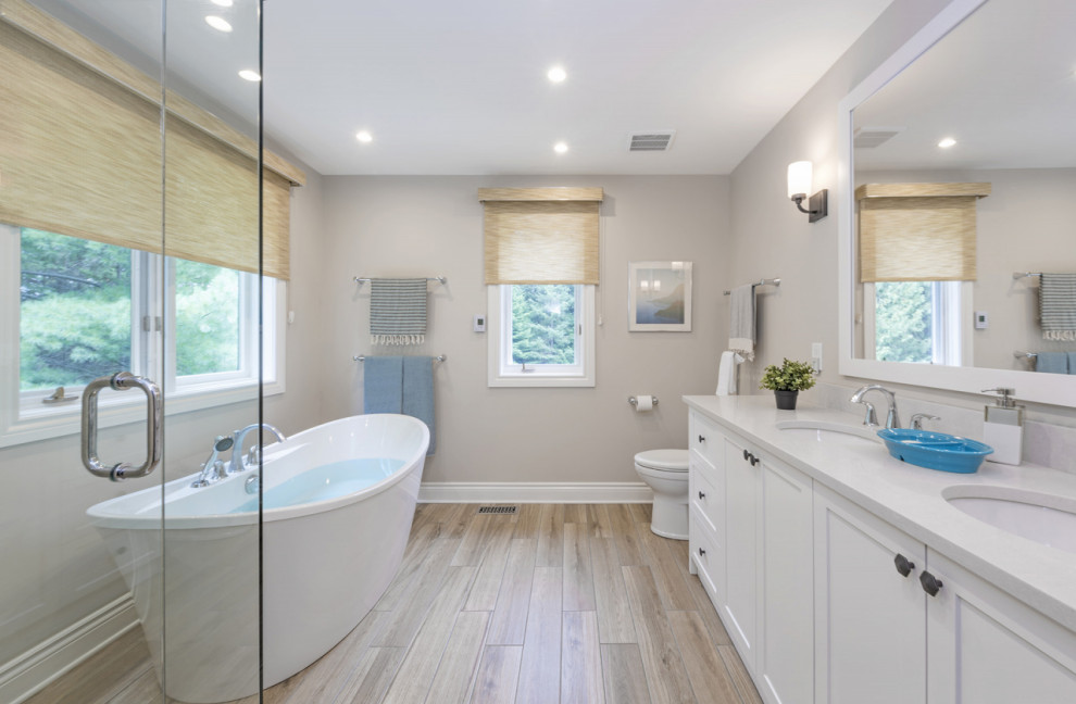 Large transitional master beige floor corner shower photo in DC Metro with shaker cabinets, white cabinets, a two-piece toilet, gray walls, an undermount sink, a hinged shower door and white countertops