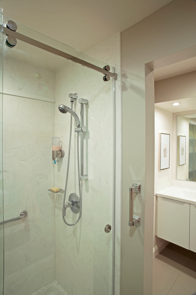 Imagen de cuarto de baño principal actual con armarios con paneles lisos, puertas de armario blancas, encimera de mármol, lavabo integrado, paredes blancas y suelo de baldosas de cerámica