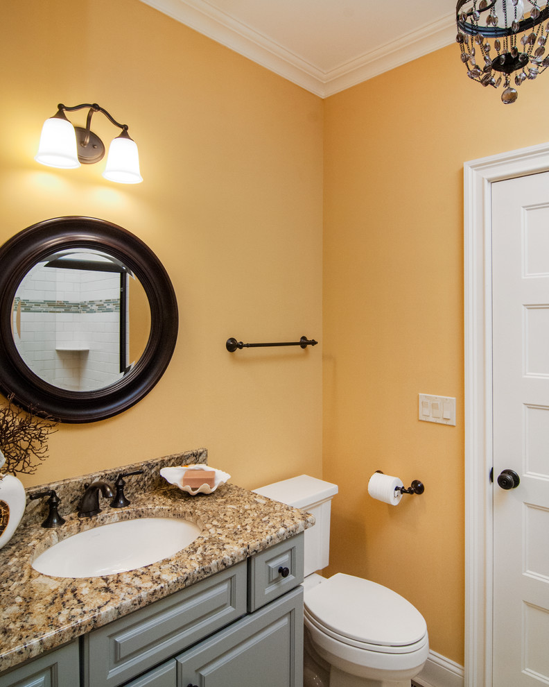 Cette photo montre une salle de bain chic de taille moyenne pour enfant avec un lavabo encastré, un placard avec porte à panneau surélevé, des portes de placard grises, un plan de toilette en granite, WC séparés et un mur jaune.