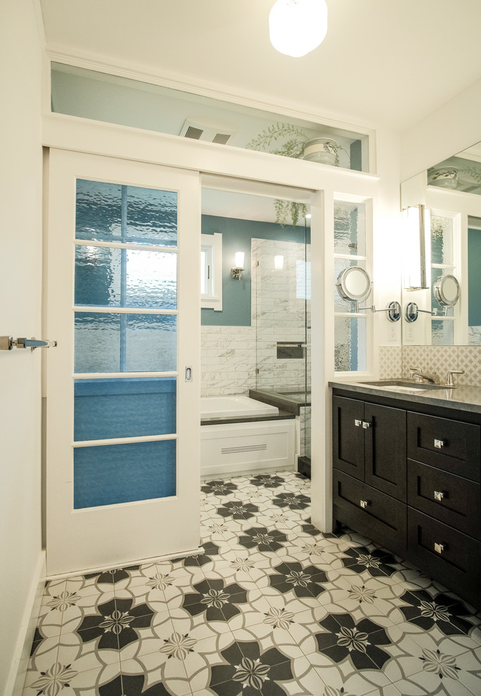 This is an example of a medium sized eclectic ensuite bathroom in Seattle with recessed-panel cabinets, black cabinets, a built-in bath, a corner shower, a two-piece toilet, white tiles, marble tiles, white walls, ceramic flooring, a submerged sink, limestone worktops, multi-coloured floors, a hinged door and grey worktops.