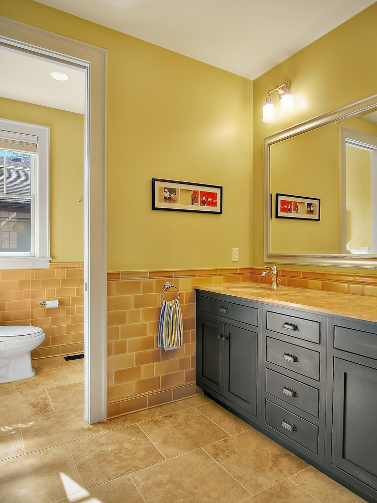 На фото: большая главная ванная комната в стиле кантри с фасадами в стиле шейкер, черными фасадами, раздельным унитазом, бежевой плиткой, керамической плиткой, желтыми стенами, полом из травертина, врезной раковиной, столешницей из гранита и бежевым полом