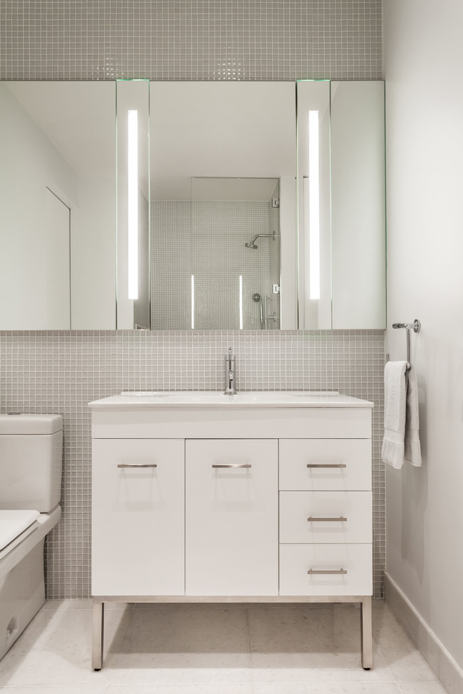 Small minimalist master white tile and glass tile marble floor corner shower photo in New York with an undermount sink, furniture-like cabinets, white cabinets, a one-piece toilet and white walls