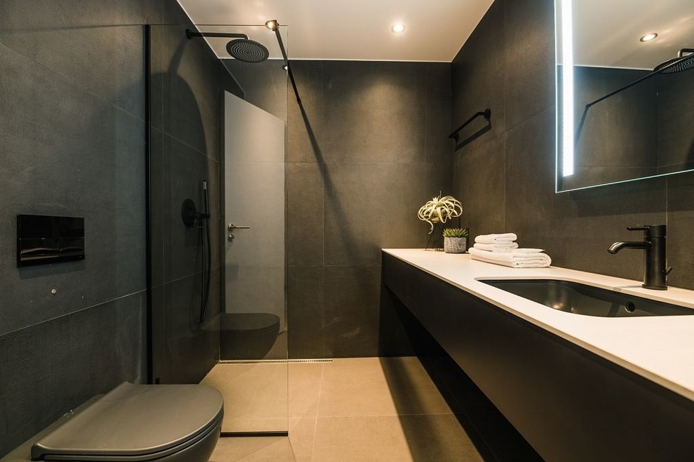 Идея дизайна: главная ванная комната в скандинавском стиле с черными фасадами, черной плиткой, керамогранитной плиткой, черными стенами, полом из керамической плитки, монолитной раковиной, столешницей из плитки, бежевым полом и белой столешницей