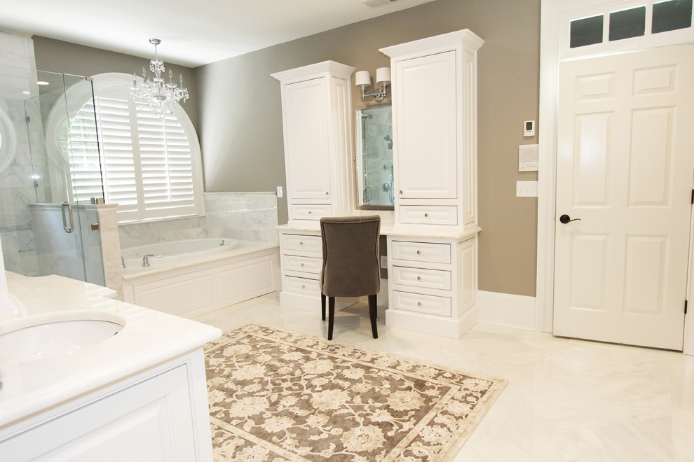 Cette image montre une très grande salle de bain principale traditionnelle avec un lavabo encastré, des portes de placard blanches, un plan de toilette en marbre, une baignoire posée, une douche à l'italienne, WC séparés, un carrelage blanc, un carrelage de pierre, un mur gris et un sol en marbre.