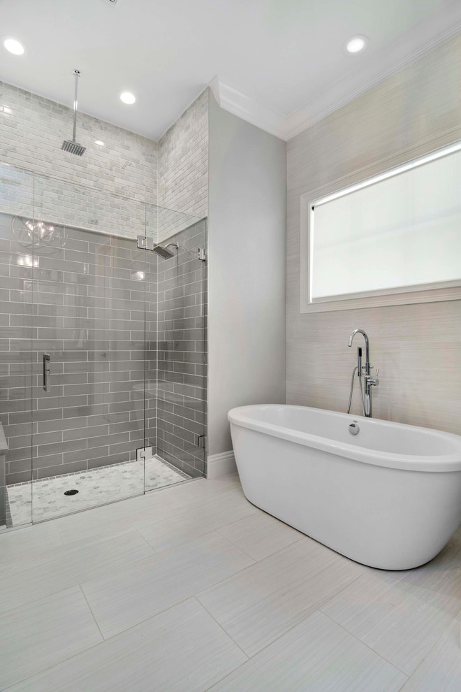 Klassisk inredning av ett stort en-suite badrum, med ett fristående badkar, en kantlös dusch, tunnelbanekakel, grå väggar, klinkergolv i keramik, ett undermonterad handfat, grått golv, dusch med gångjärnsdörr och flerfärgad kakel