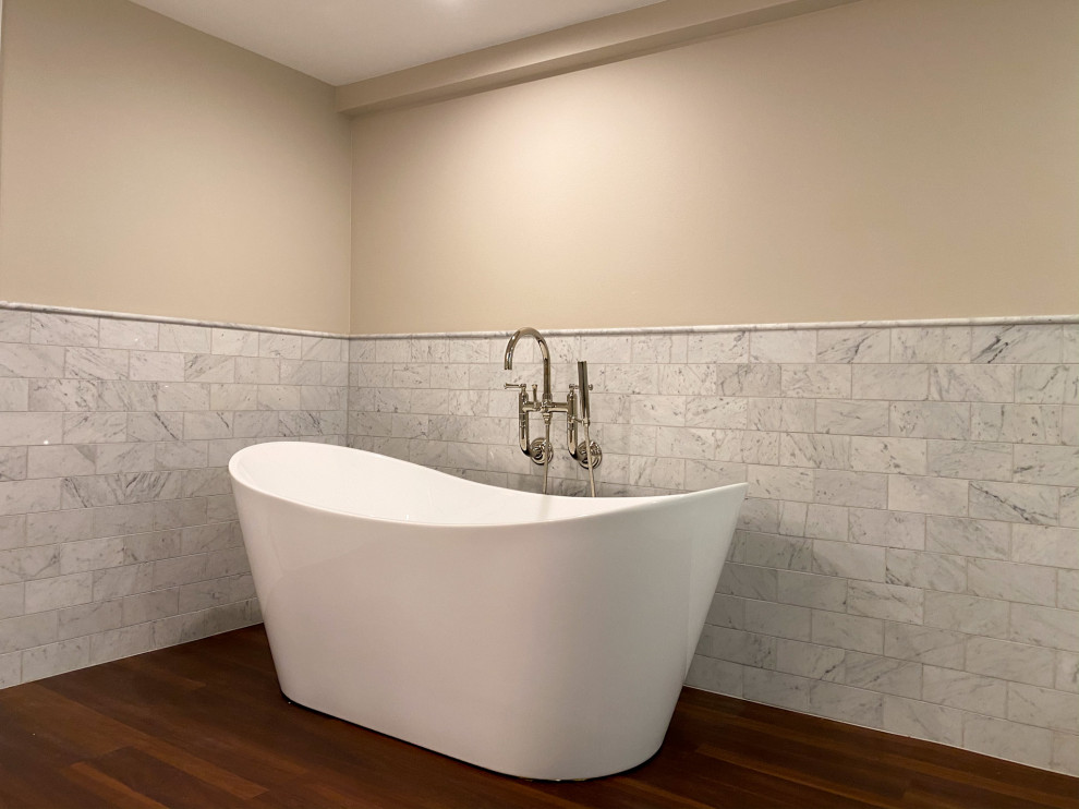 Пример оригинального дизайна: большая главная ванная комната в стиле кантри с фасадами в стиле шейкер, белыми фасадами, отдельно стоящей ванной, открытым душем, раздельным унитазом, белой плиткой, мраморной плиткой, бежевыми стенами, полом из винила, врезной раковиной, столешницей из искусственного кварца, коричневым полом, душем с распашными дверями, розовой столешницей, тумбой под две раковины и встроенной тумбой
