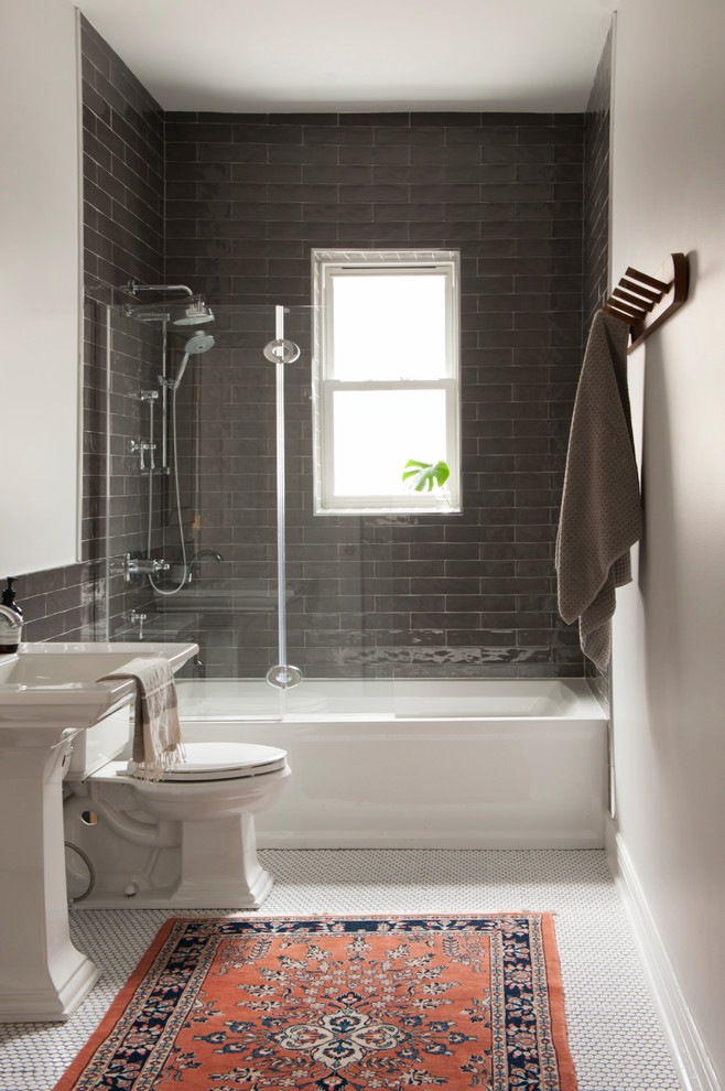 Modelo de cuarto de baño clásico con bañera encastrada, combinación de ducha y bañera, baldosas y/o azulejos grises, paredes beige, suelo con mosaicos de baldosas, lavabo con pedestal, suelo blanco y ducha abierta