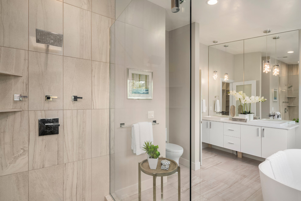 Idéer för mellanstora funkis en-suite badrum, med släta luckor, vita skåp, ett fristående badkar, en dusch i en alkov, grå kakel, stenkakel, grå väggar, klinkergolv i porslin, ett nedsänkt handfat, bänkskiva i akrylsten, beiget golv och dusch med gångjärnsdörr