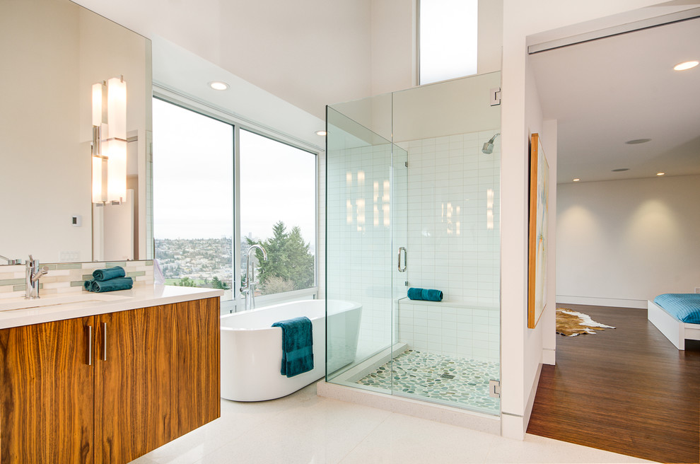 Cette photo montre une salle de bain moderne en bois brun avec un placard à porte plane, une baignoire indépendante, un sol en galet et un sol blanc.