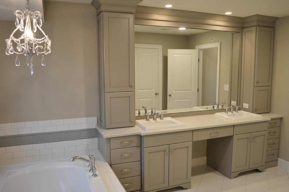 Exemple d'une salle de bain principale chic de taille moyenne avec un placard avec porte à panneau surélevé, des portes de placard grises, une baignoire posée, un sol en carrelage de céramique, un plan de toilette en quartz, un sol blanc, un carrelage blanc, un carrelage métro, un mur gris et un lavabo posé.