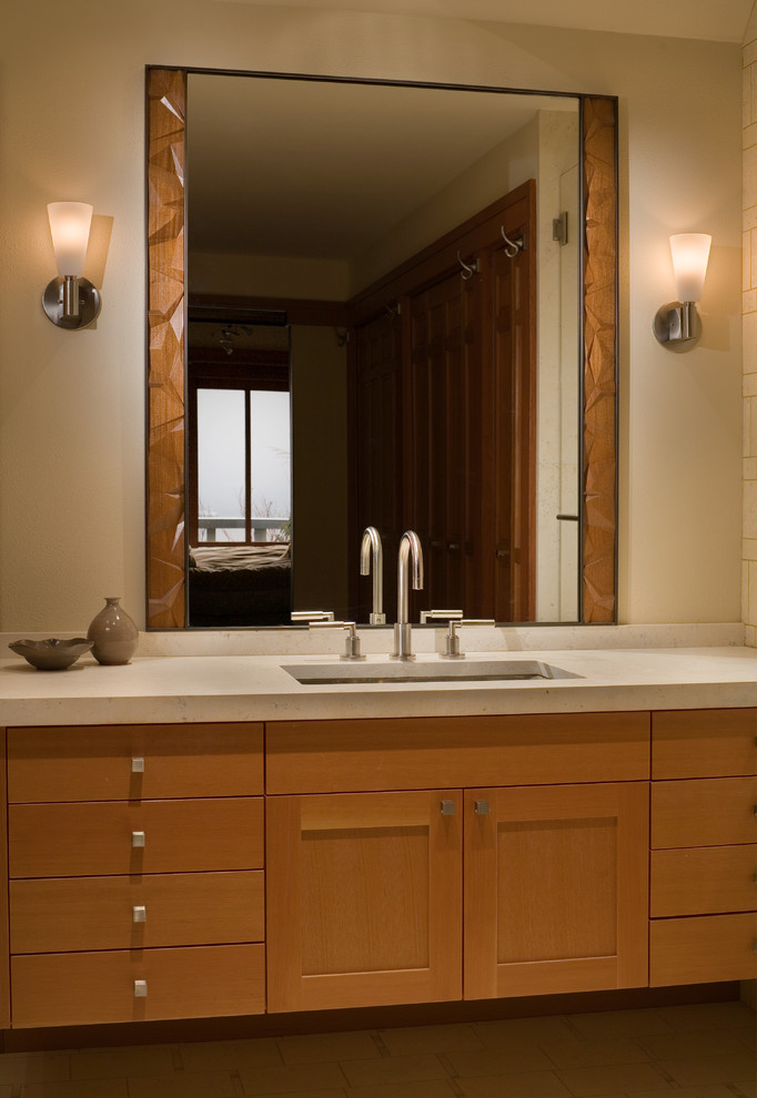 Imagen de cuarto de baño moderno pequeño con lavabo bajoencimera, armarios estilo shaker, puertas de armario de madera oscura, encimera de piedra caliza, suelo de piedra caliza y aseo y ducha