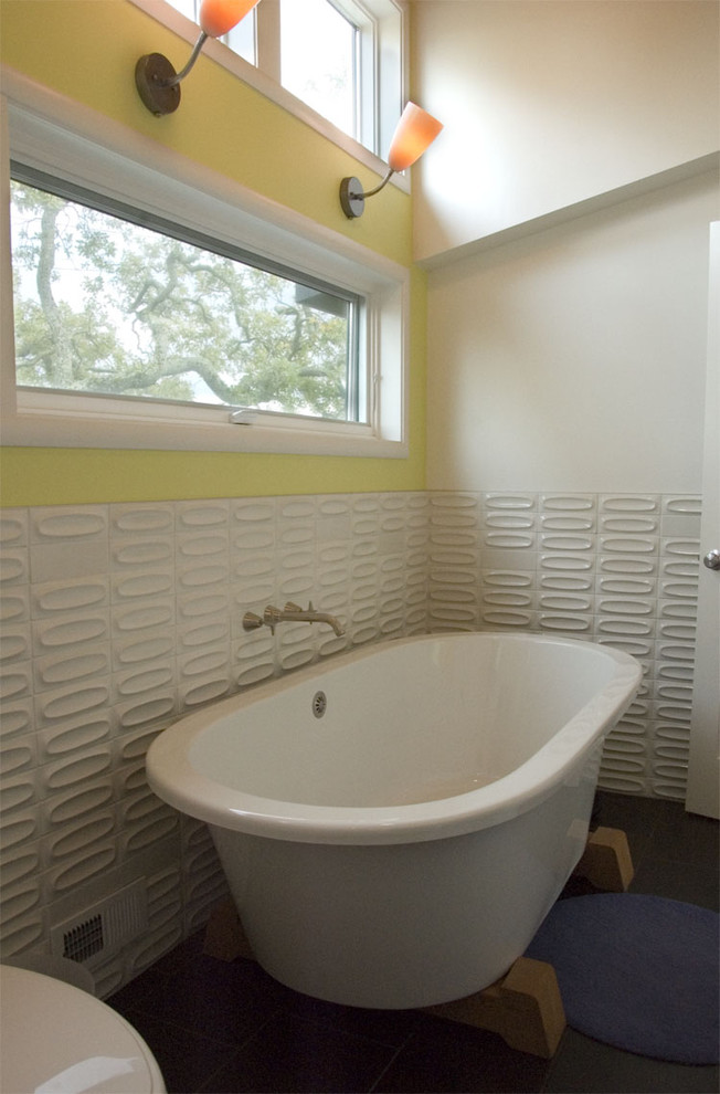 Exempel på ett mellanstort modernt en-suite badrum, med ett fristående badkar, keramikplattor, gula väggar, skiffergolv och vit kakel