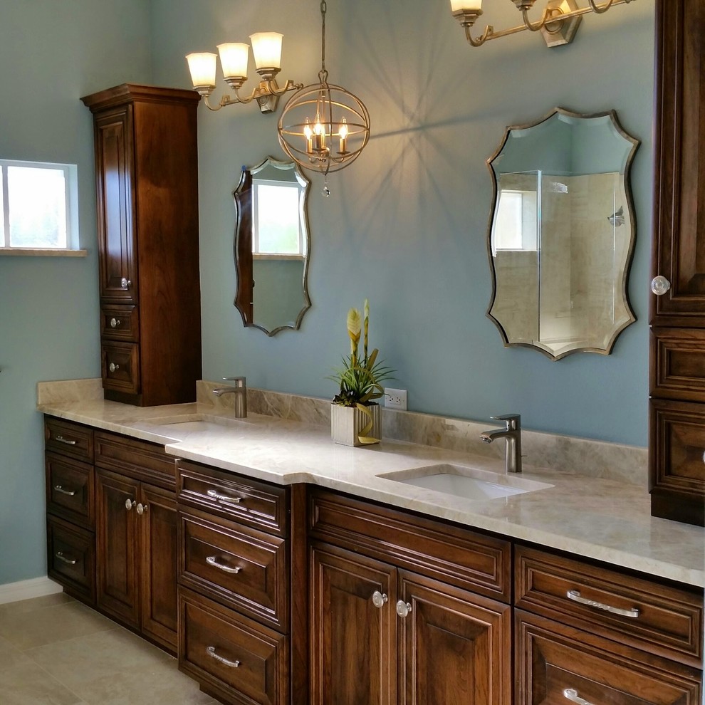 Foto di una stanza da bagno padronale tradizionale di medie dimensioni con lavabo sottopiano, ante con bugna sagomata, ante in legno bruno, top in granito, pareti blu e pavimento in gres porcellanato