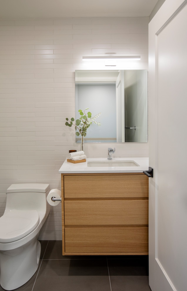 Immagine di una stanza da bagno moderna con vasca/doccia, WC monopezzo, piastrelle bianche, piastrelle in gres porcellanato, pavimento in gres porcellanato, lavabo sottopiano, pavimento grigio e doccia con tenda