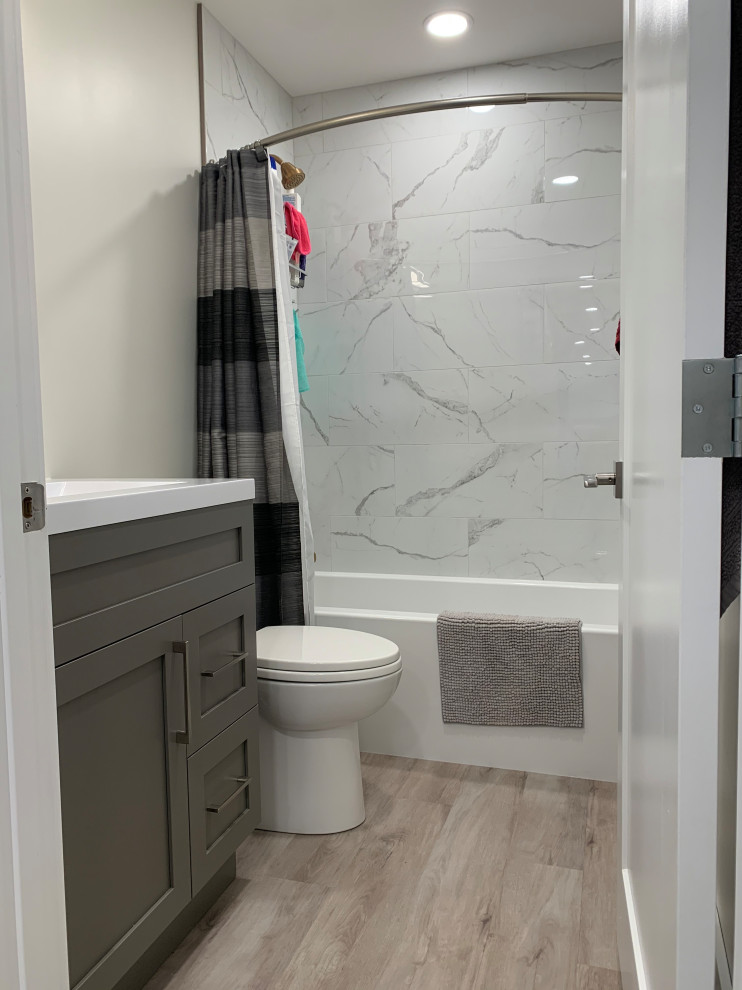 Aménagement d'une petite salle de bain contemporaine avec un placard à porte shaker, des portes de placard grises, un combiné douche/baignoire, WC à poser, un carrelage blanc, des carreaux de céramique, un mur blanc, un sol en vinyl, un lavabo intégré, un plan de toilette en quartz modifié, un sol gris, une cabine de douche avec un rideau, un plan de toilette blanc, meuble simple vasque et meuble-lavabo encastré.